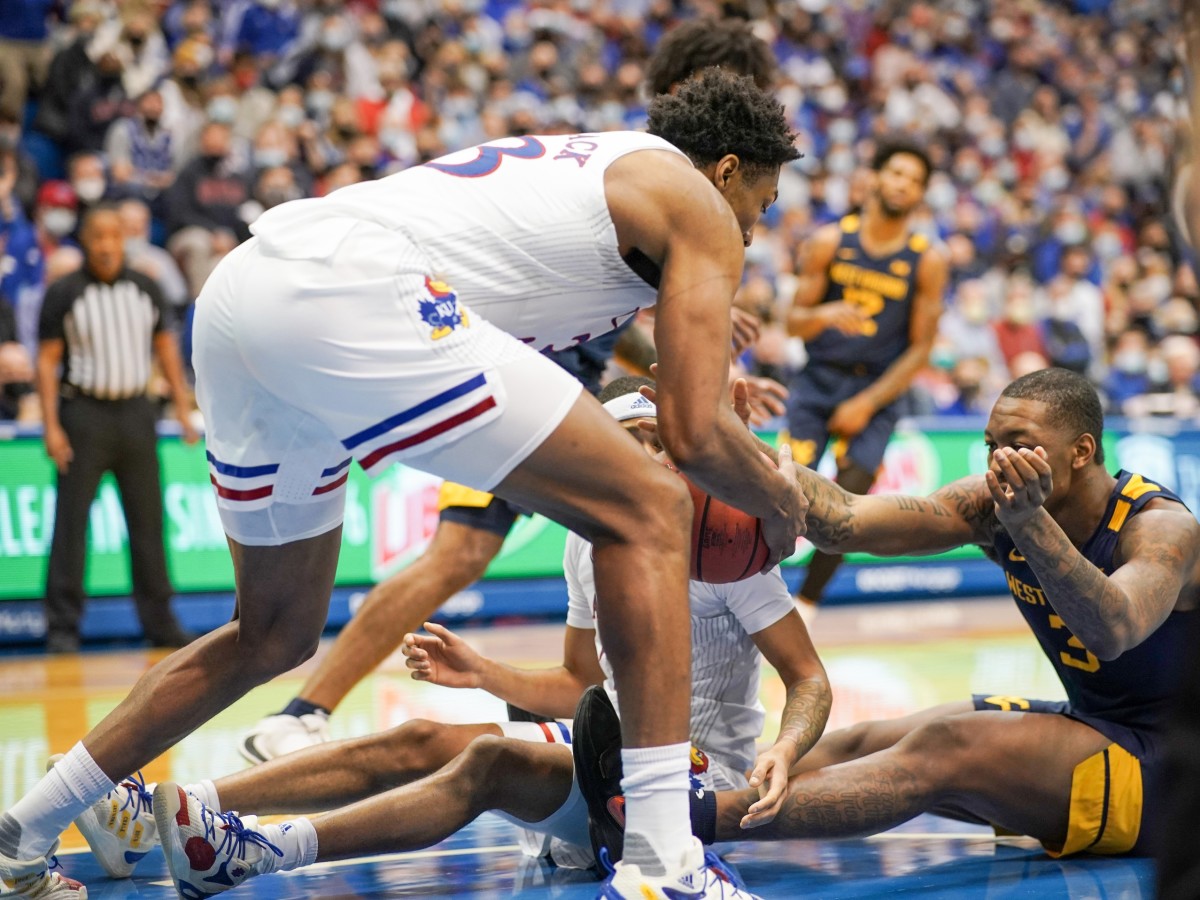 Jan 15, 2022; Lawrence, Kansas, USA; Kansas Jayhawks forward David McCormack (33) and guard Dajuan Harris Jr. (3) and West Virginia Mountaineers forward Gabe Osabuohien (3) fight for a loose ball during the first half at Allen Fieldhouse.