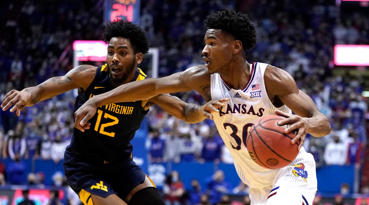 Kansas guard Ochai Agbaji (30) drives to the basket against West Virginia guard Taz Sherman (12) in the first half of an NCAA college basketball game Tuesday, Jan. 15, 2022, in Lawrence, Kan.