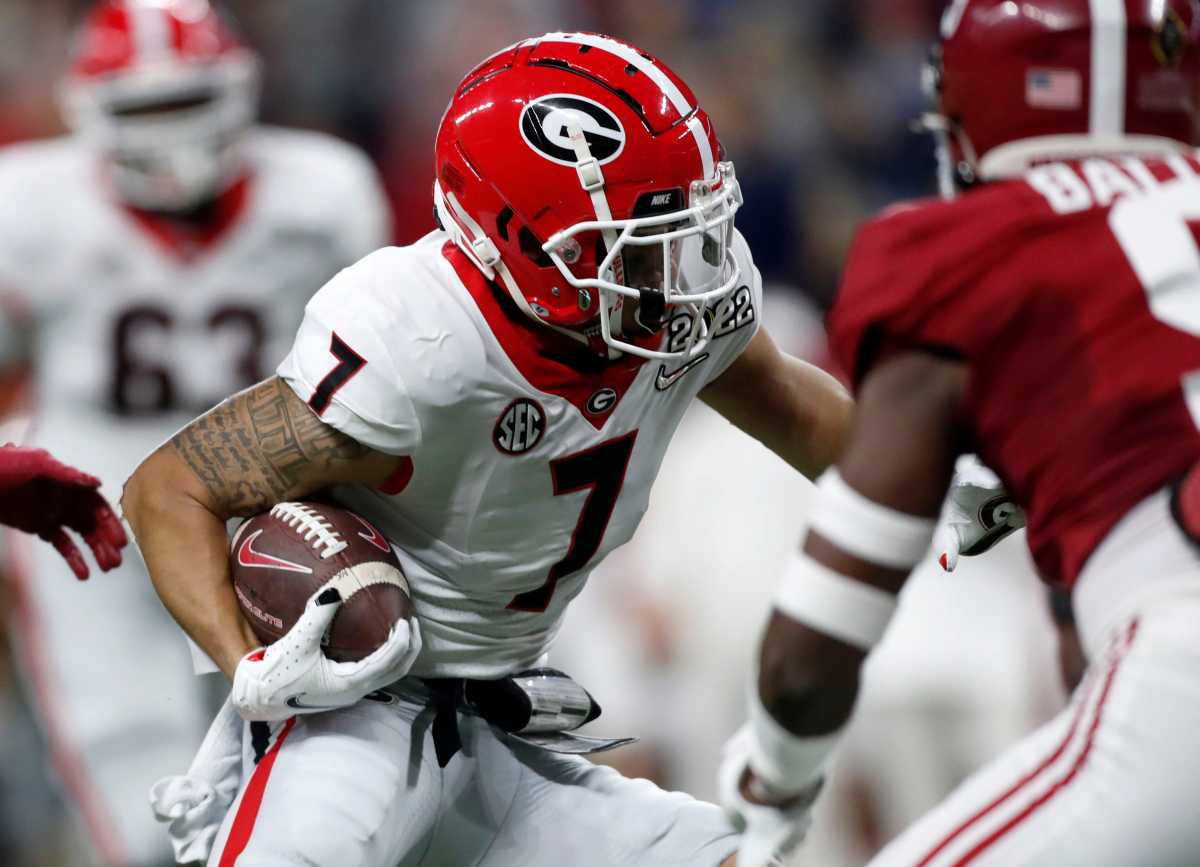 Georgia Bulldogs wide receiver Jermaine Burton (7) moves the ball between Alabama Crimson Tide defenders Monday, Jan. 10, 2022, during the College Football Playoff National Championship at Lucas Oil Stadium in Indianapolis.
