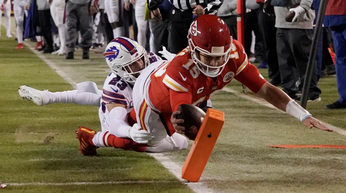 Kansas City Chiefs quarterback Patrick Mahomes (15) scores on an 8-yard touchdown run ahead of Buffalo Bills safety Micah Hyde (23) during the first half of an NFL divisional round playoff football game, Sunday, Jan. 23, 2022, in Kansas City, Mo.