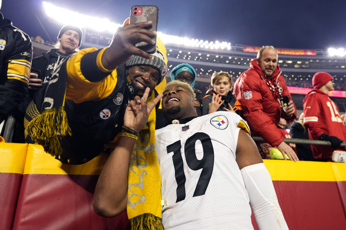 Jan 16, 2022; Kansas City, Missouri, USA; Pittsburgh Steelers wide receiver JuJu Smith-Schuster (19) poses for a photograph with a fan following the game against the Kansas City Chiefs in an AFC Wild Card playoff football game at GEHA Field at Arrowhead Stadium. Mandatory Credit: Jay Biggerstaff-USA TODAY Sports