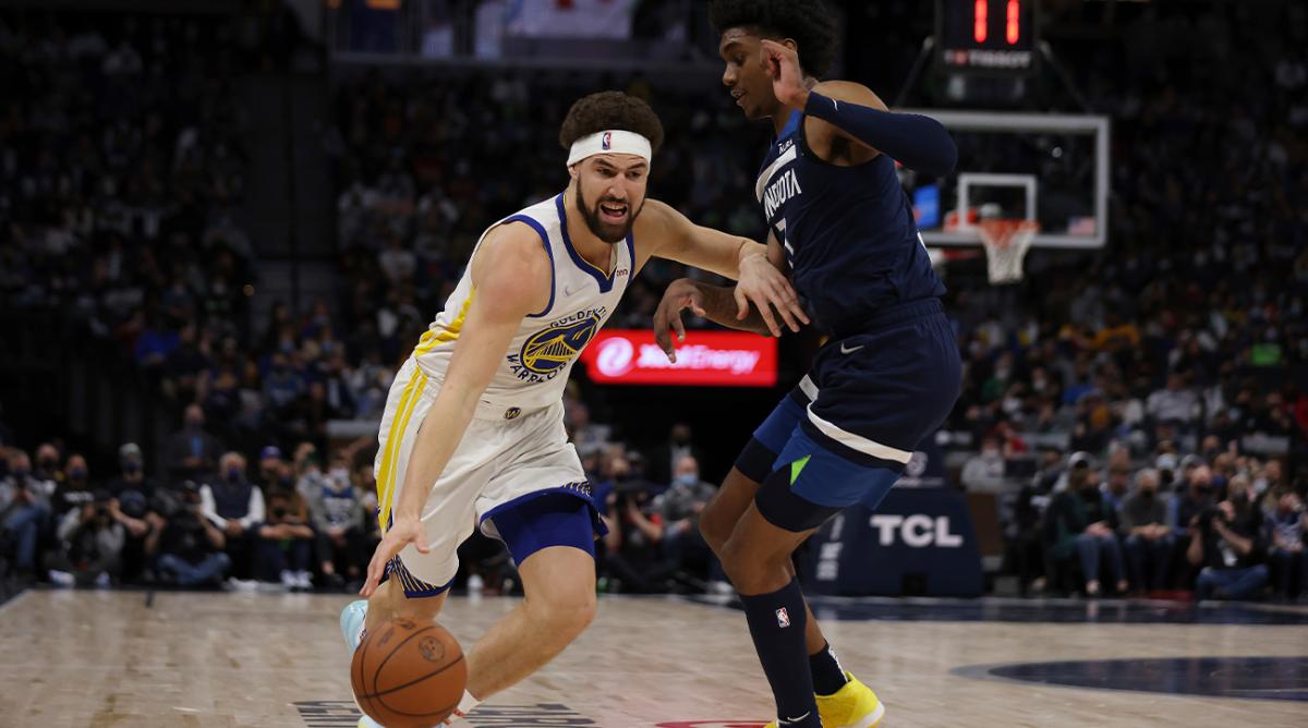 Golden State Warriors guard Klay Thompson (11) handles the ball against Minnesota Timberwolves forward Jaden McDaniels (3) during the second half of an NBA basketball game, Sunday, Jan. 16, 2022, in Minneapolis.