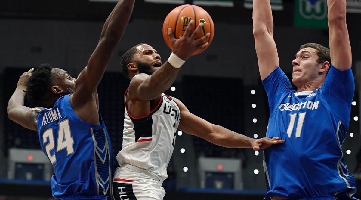 Connecticut's R.J. Cole shoots between Creighton's Arthur Kaluma (24) and Creighton's Ryan Kalkbrenner (11) in the first half of an NCAA college basketball game, Tuesday, Feb. 1, 2022, in Hartford, Conn.