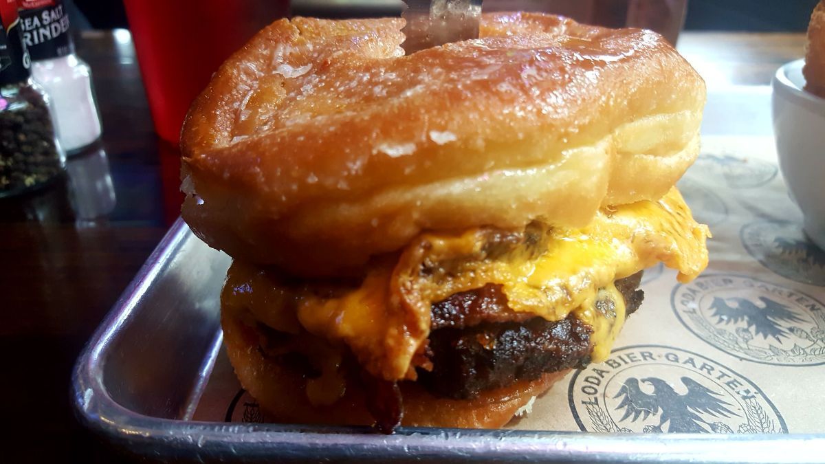 A bacon cheeseburger with Abita Root Beer BBQ sauce topped with caramelized onions on two glazed donuts at Loda Bier Garten in Mobile, Ala.