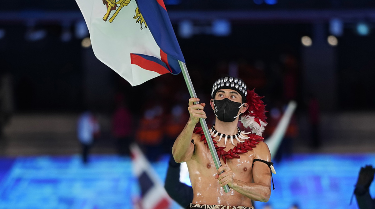 Nathan Crumpton, of American Samoa, carries his national flag into the stadium during the opening ceremony of the 2022 Winter Olympics, Friday, Feb. 4, 2022, in Beijing.