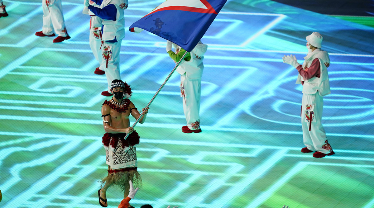 Nathan Crumpton, of American Samoa, carries his national flag into the stadium during the opening ceremony of the 2022 Winter Olympics, Friday, Feb. 4, 2022, in Beijing.