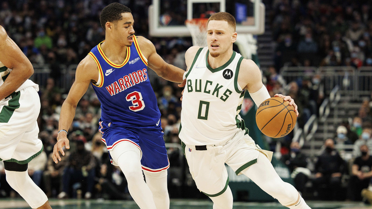 Milwaukee Bucks guard Donte DiVincenzo (0) drives for the basket around Golden State Warriors guard Jordan Poole.