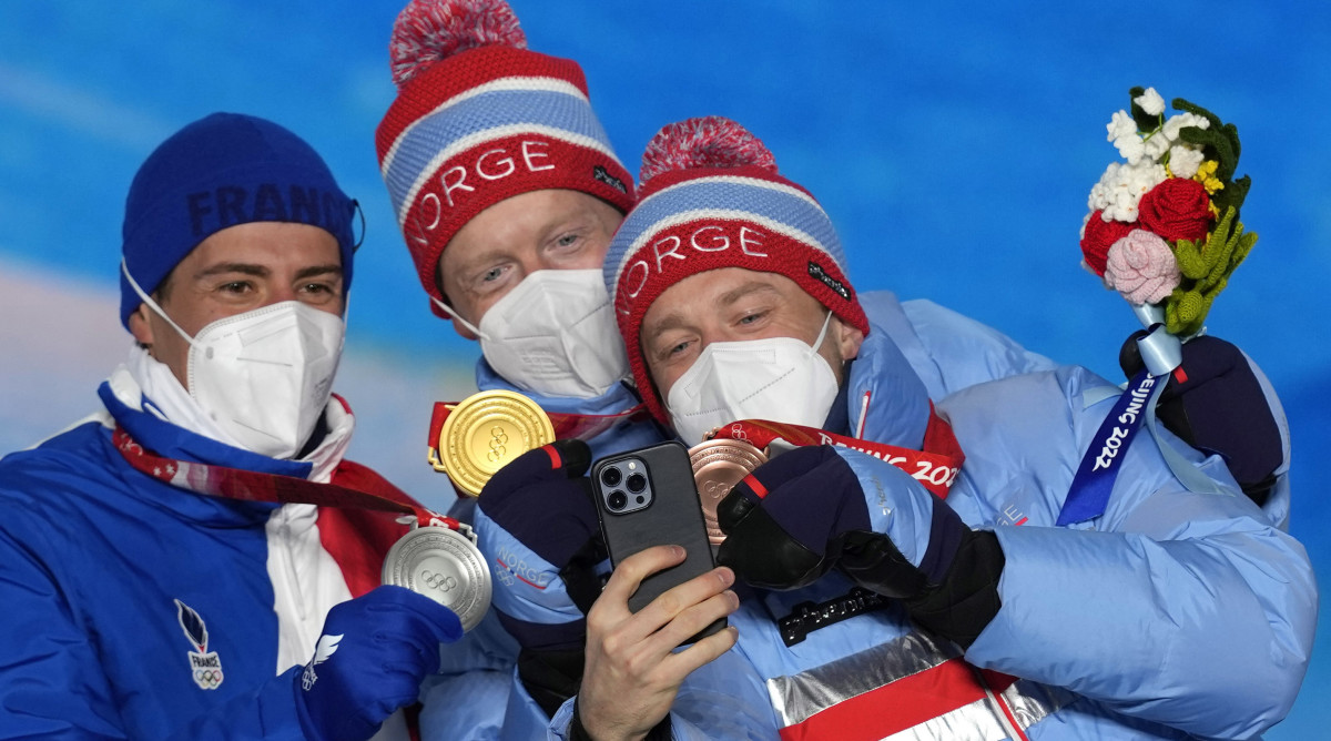Norway's Johannes Thingnes Bø, center, and Tarjei Bø, right, pose for a selfie. 