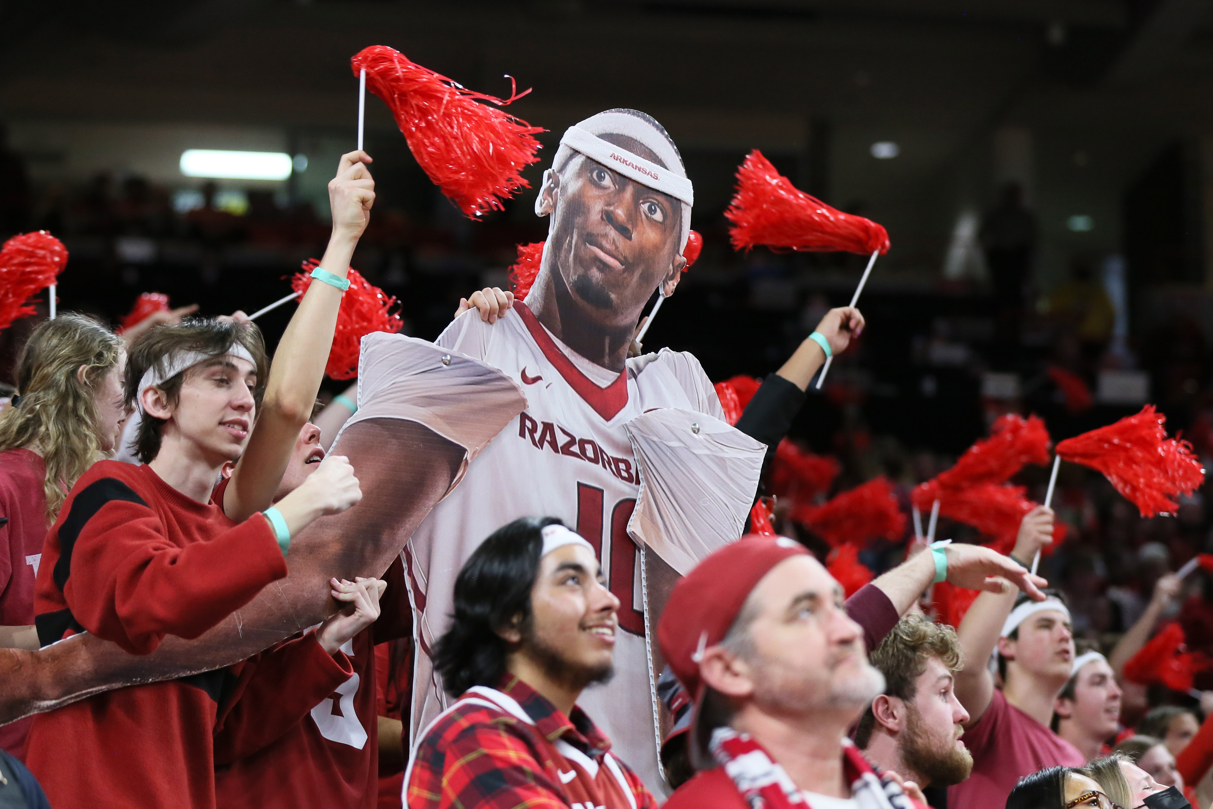Arkansas fans get into the spirt of Bobby Portis night with a cut-out puppet wearing the Bobby Portis head band given away at the game while also waiving the pom-poms they received for the red-out.