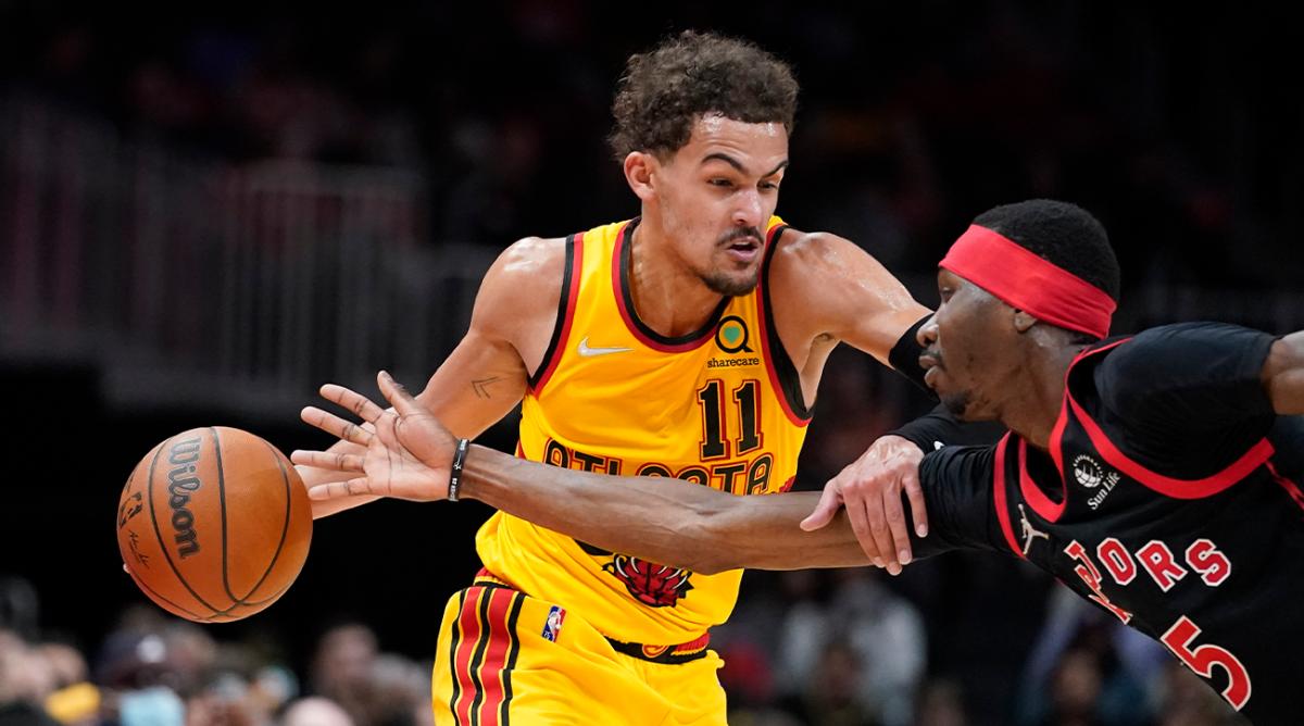 Atlanta Hawks guard Trae Young (11) tries to fend off Toronto Raptors forward Chris Boucher (25) in the first half of an NBA basketball game, Saturday, Feb. 26, 2022, in Atlanta.