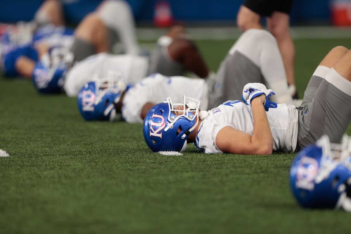 Rows of Kansas players go through stretching exercises during practice Tuesday morning in Lawrence.