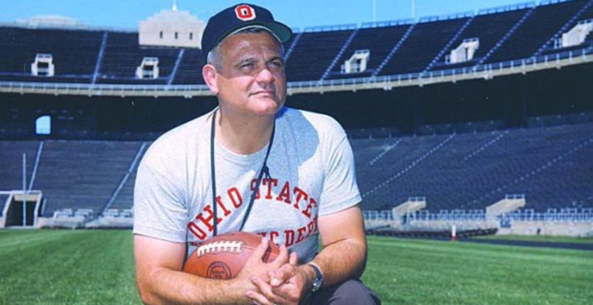 Ohio State Buckeyes head coach and College Football Hall of Famer Woody Hayes kneels on the field at Ohio Stadium.