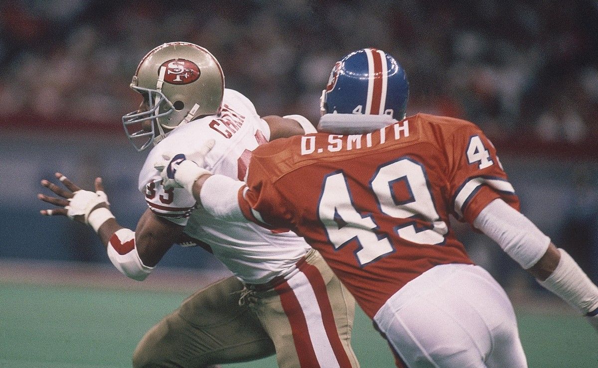 San Francisco 49ers running back Roger Craig (33) carries the ball against Denver Broncos defensive back Dennis Smith (49) during Super Bowl XXIV at the Superdome. The 49ers defeated the Broncos 55-10.