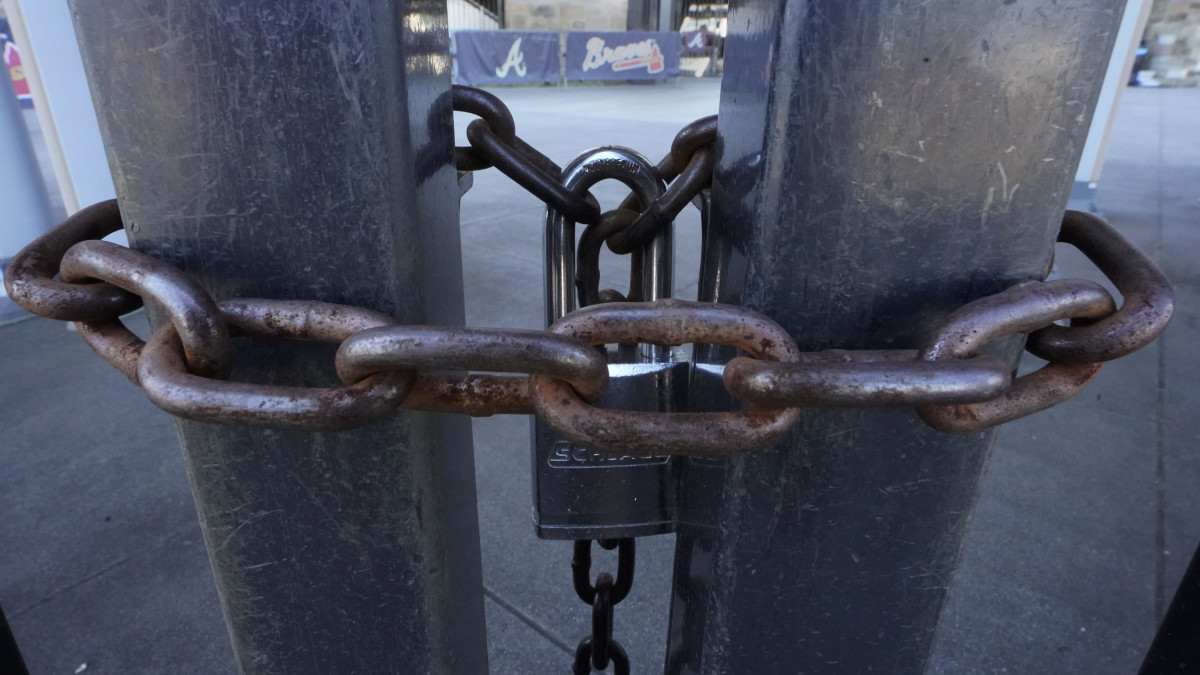 Locked gates are shown at Truist Park, home of the Atlanta Braves baseball team, Wednesday, March 2, 2022, in Atlanta. With owners and players unable to agree on a labor contract to replace the collective bargaining agreement that expired Dec. 1, baseball commissioner Rob Manfred followed through with his threat on Tuesday and canceled the first two series for each of the 30 major league teams. (AP Photo/John Bazemore)