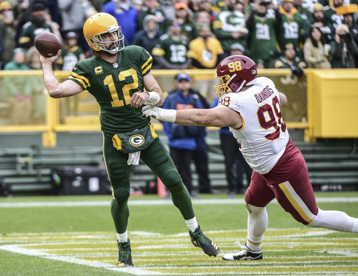Oct 24, 2021; Green Bay, Wisconsin, USA; Green Bay Packers quarterback Aaron Rodgers (12) gets a pass away while under pressure from Washington Football Team defensive tackle Matt Ioannidis (98) in the third quarter at Lambeau Field. Mandatory Credit: Benny Sieu-USA TODAY Sports