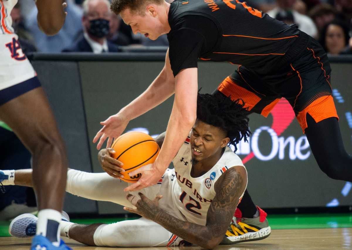 Auburn Tigers guard Zep Jasper (12) and Miami Hurricanes forward Sam Waardenburg (21) go after a loose ball during the second round of the 2022 NCAA tournament at Bon Secours Wellness Arena in Greenville, S.C., on Sunday, March 20, 2022. Miami Hurricanes lead Auburn Tigers 33-32 at halftime.
