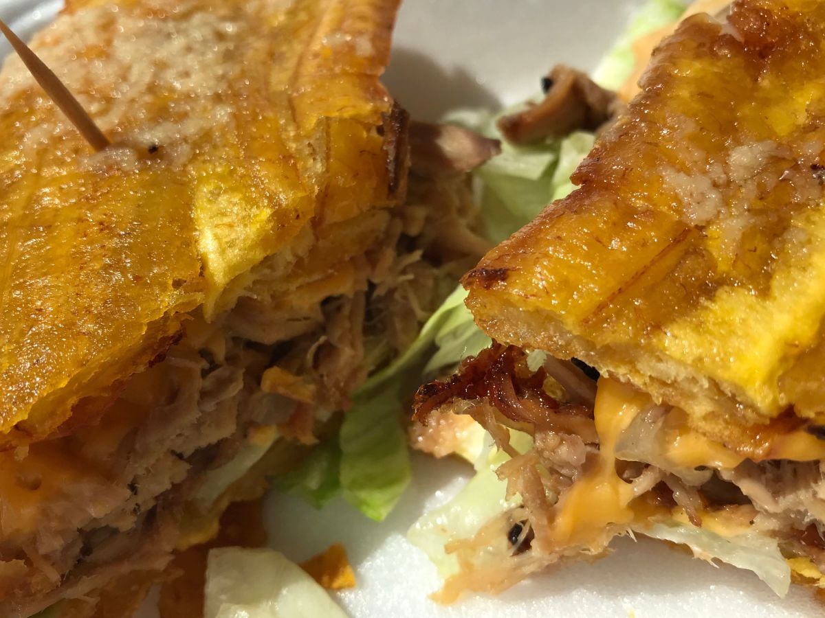 A jibarito with roasted pork from Shalom Puerto Rican Restaurant. The sandwich, made with fried green plantain in place of bread, is naturally gluten free. Depcol22 Shalom Jibarito