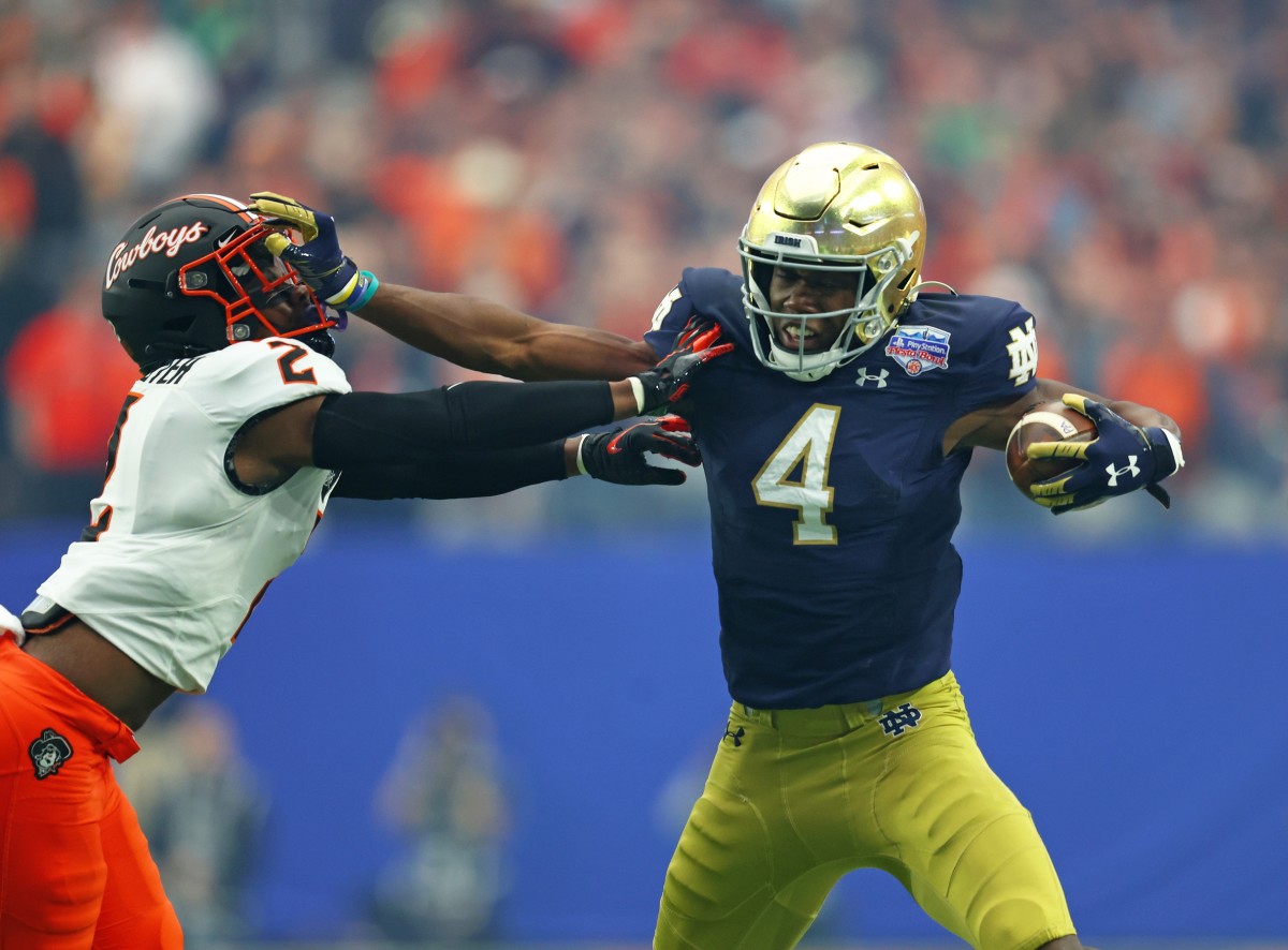 Jan 1, 2022; Glendale, Arizona, USA; Notre Dame Fighting Irish wide receiver Kevin Austin Jr. (4) stiff arms Oklahoma State Cowboys safety Tanner McCalister (2) in the first half during the 2022 Fiesta Bowl at State Farm Stadium. Mandatory Credit: Mark J. Rebilas-USA TODAY Sports