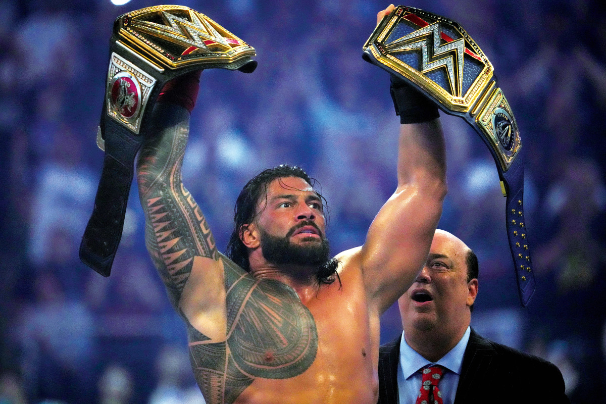 Roman Reigns holds up the WWE championship and the Universal championship after unifying them with a victory over Brock Lesnar at WrestleMania 38 at AT&T Stadium in Arlington.