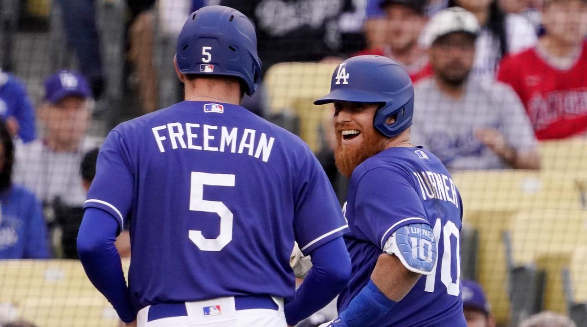 Los Angeles Dodgers’ Justin Turner, right, smiles at Freddie Freeman after he hit a sacrifice fly that allowed Freeman to score during the first inning of a spring training baseball game against the Los Angeles Angels Monday, April 4, 2022, in Los Angeles.