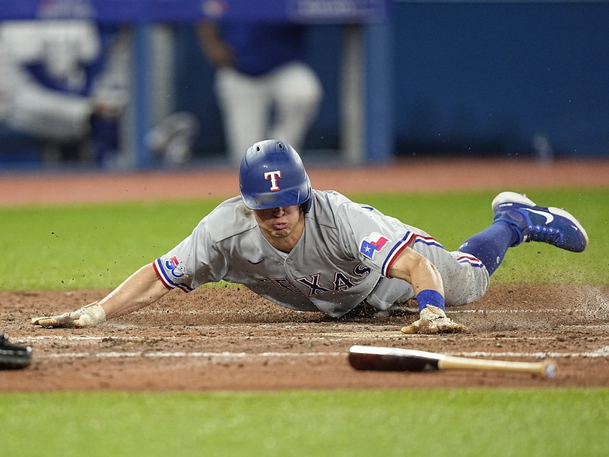 Apr 10, 2022; Toronto, Ontario, CAN; Texas Rangers left fielder Nick Solak (15) slides into home plate to score against the Toronto Blue Jays during the fifth inning at Rogers Centre. Mandatory Credit: John E. Sokolowski-USA TODAY Sports