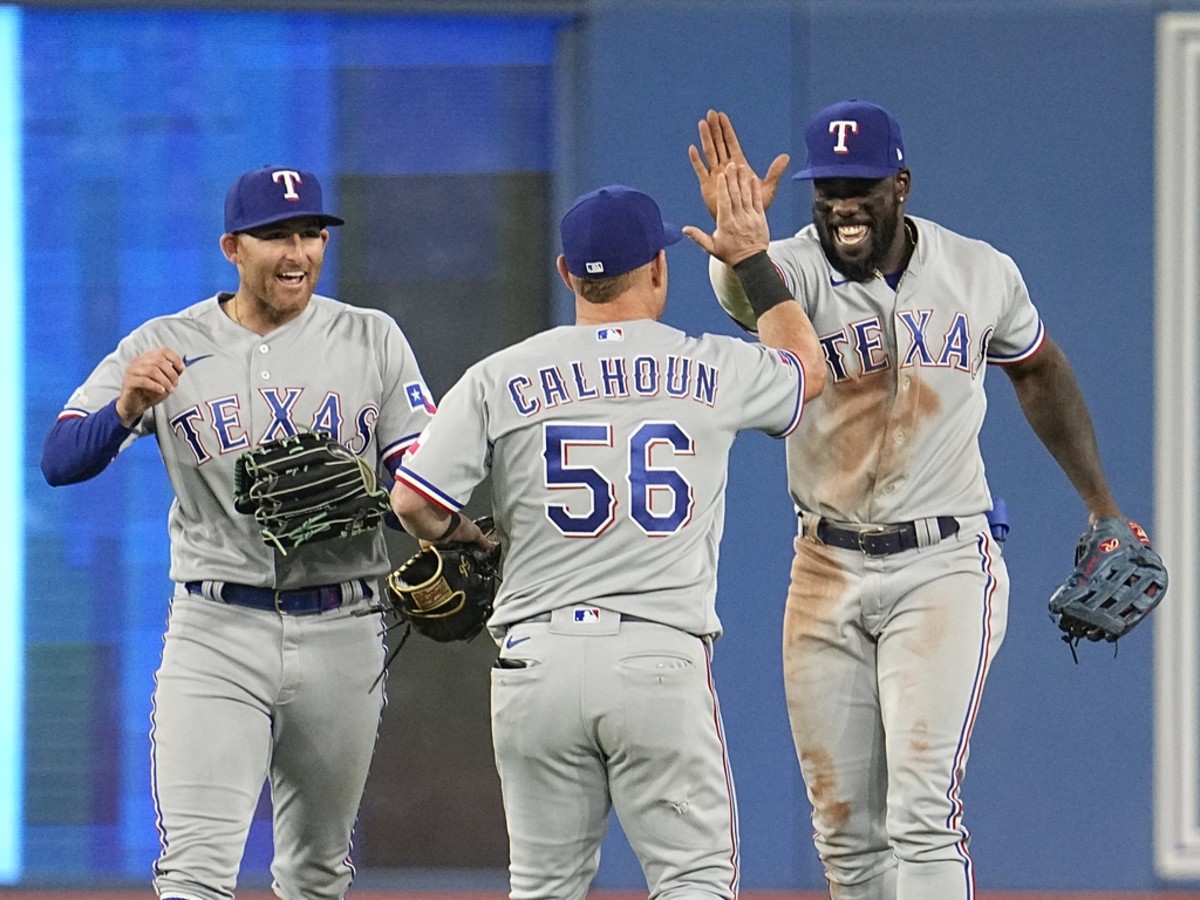 Apr 10, 2022; Toronto, Ontario, CAN; Texas Rangers left fielder Brad Miller (13) and right fielder Kole Calhoun (56) and center fielder Adolis Garcia (53) celebrate a win over the Texas Rangers during the ninth inning at Rogers Centre. Mandatory Credit: John E. Sokolowski-USA TODAY Sports