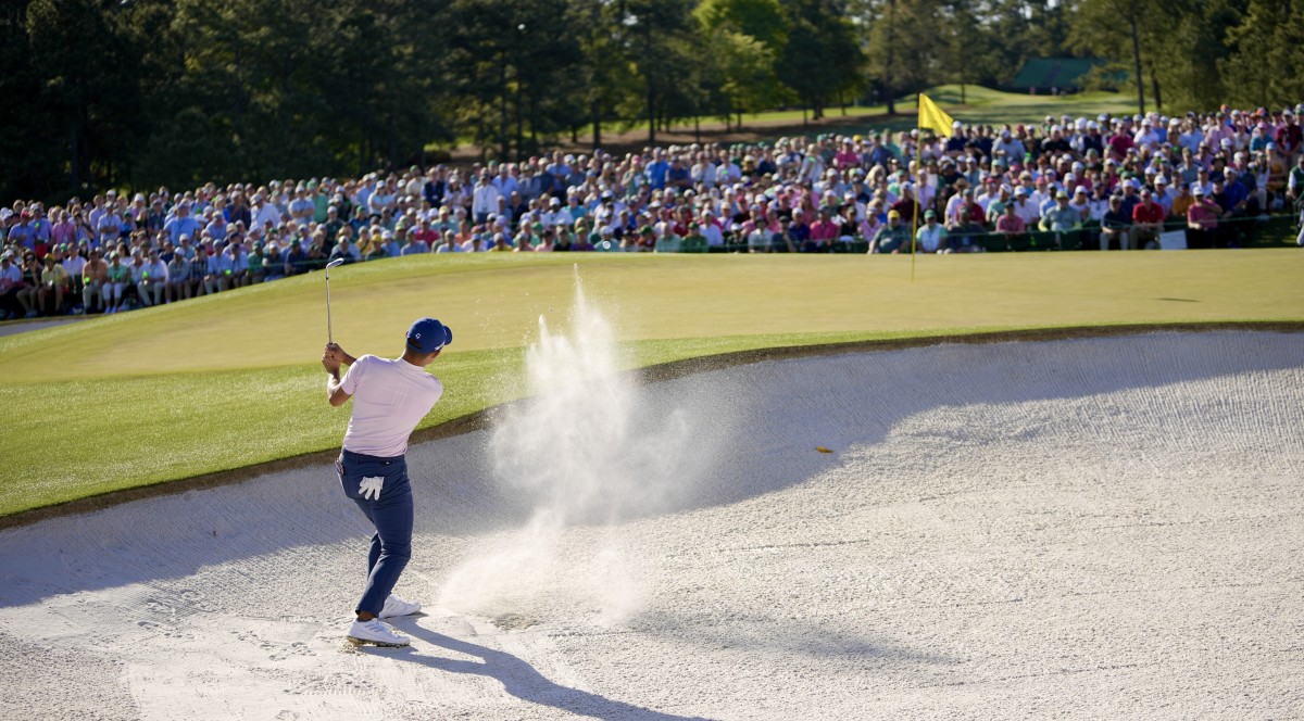 Collin Morikawa chips out of the sand on the 18th hole at the Masters