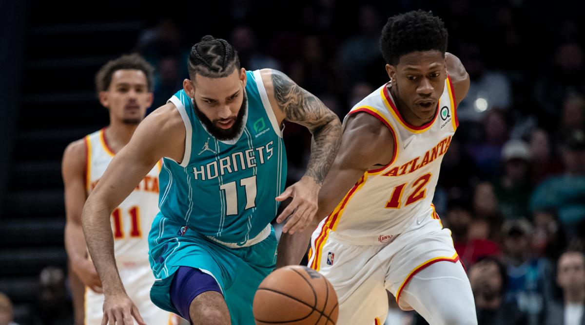 Charlotte Hornets forward Cody Martin (11) and Atlanta Hawks forward De’Andre Hunter (12) chase the ball during the second half of an NBA basketball game Wednesday, March 16, 2022, in Charlotte, N.C.