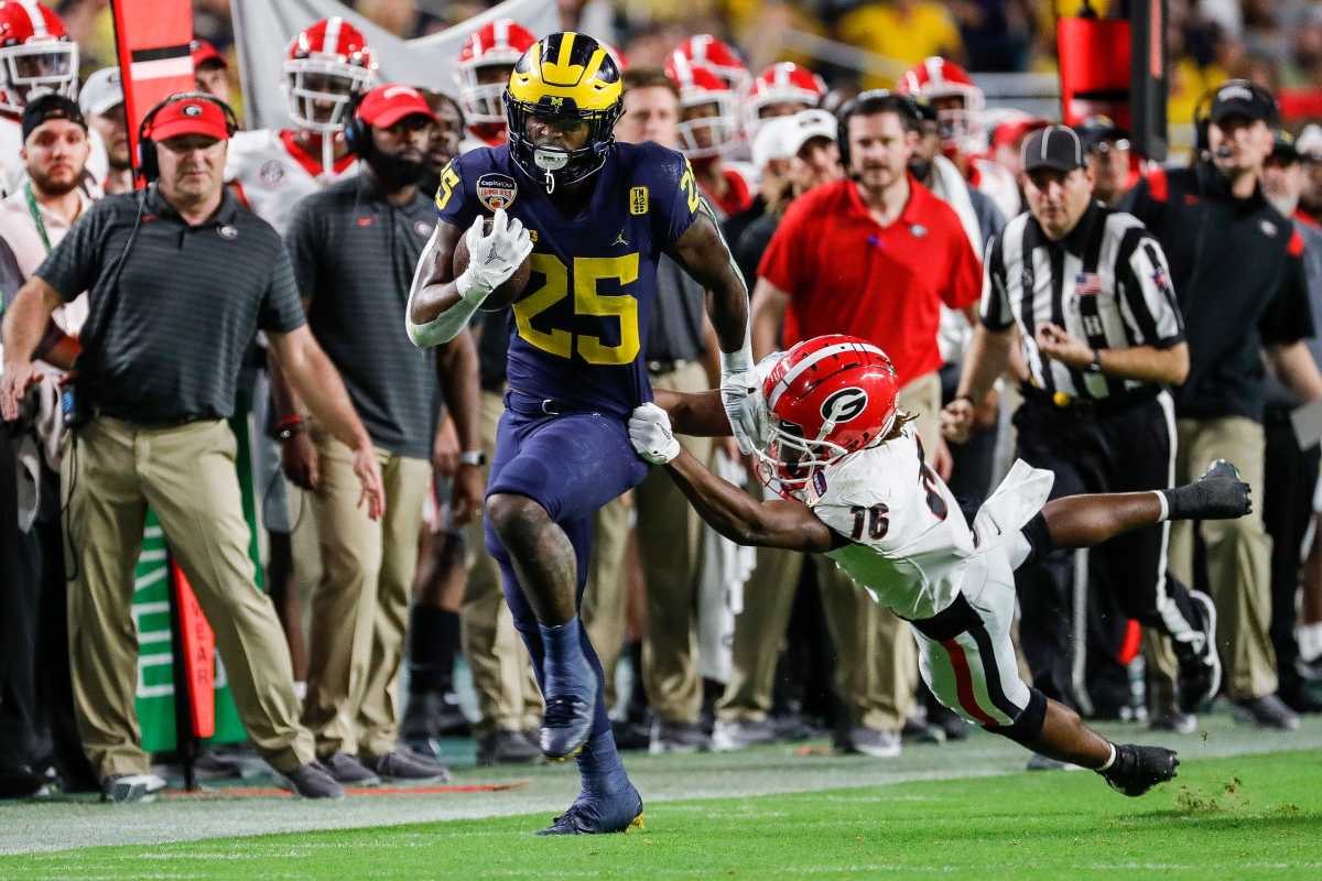 Michigan running back Hassan Haskins (25) runs against Georgia defensive back Lewis Cine (16) during the second half of the Orange Bowl at Hard Rock Stadium in Miami Gardens, Florida, on Friday, Dec. 31, 2021.