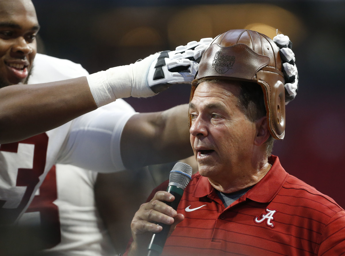 Alabama Crimson Tide offensive lineman Evan Neal (73) puts the old leather helmet on head coach Nick Saban at Mercedes-Benz Stadium after defeating the Miami Hurricanes.
