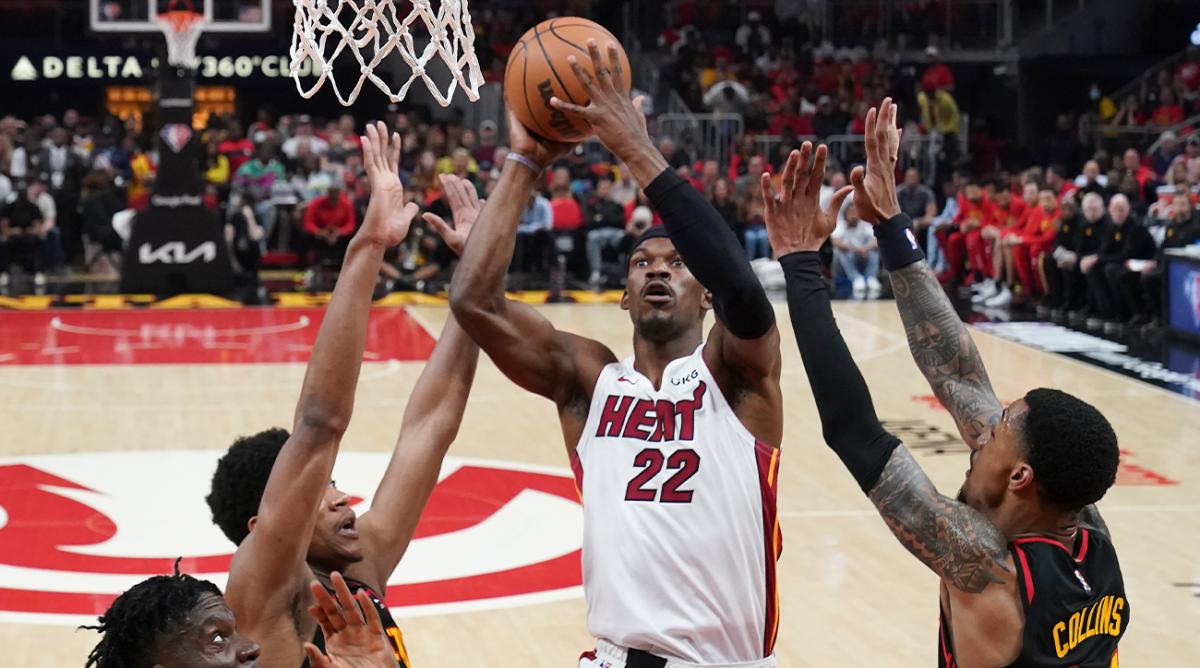 Miami Heat forward Jimmy Butler (22) goes in for a basket against Atlanta Hawks De’Andre Hunter, second from left, John Collins (20) and Clint Capela, left, in the first half of an NBA playoff basketball game Sunday, April 24, 2022, in Atlanta.