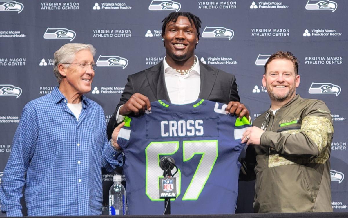 Seahawks first-round pick Charles Cross holds his new jersey alongside coach Pete Carroll and general manager John Schneider.