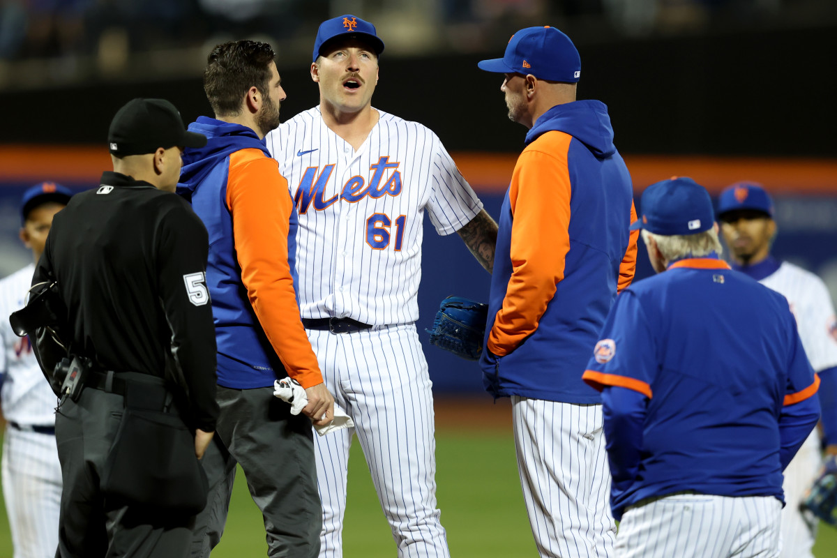Apr 30, 2022; New York City, New York, USA; New York Mets relief pitcher Sean Reid-Foley (61) talks to coaches and trainers and home plate umpire Jansen Visconti (52) before leaving the game with an apparent injury during the eighth inning against the Philadelphia Phillies at Citi Field.