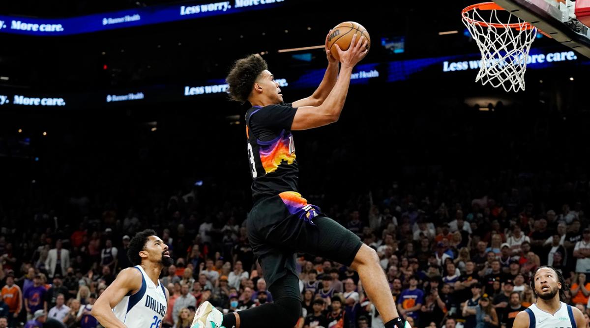 Phoenix Suns forward Cameron Johnson, middle, goes in for a dunk as Dallas Mavericks guards Spencer Dinwiddie (26) and Jalen Brunson (13) look on during the second half of Game 5 of an NBA basketball second-round playoff series Tuesday, May 10, 2022, in Phoenix. The Suns won 110-80.