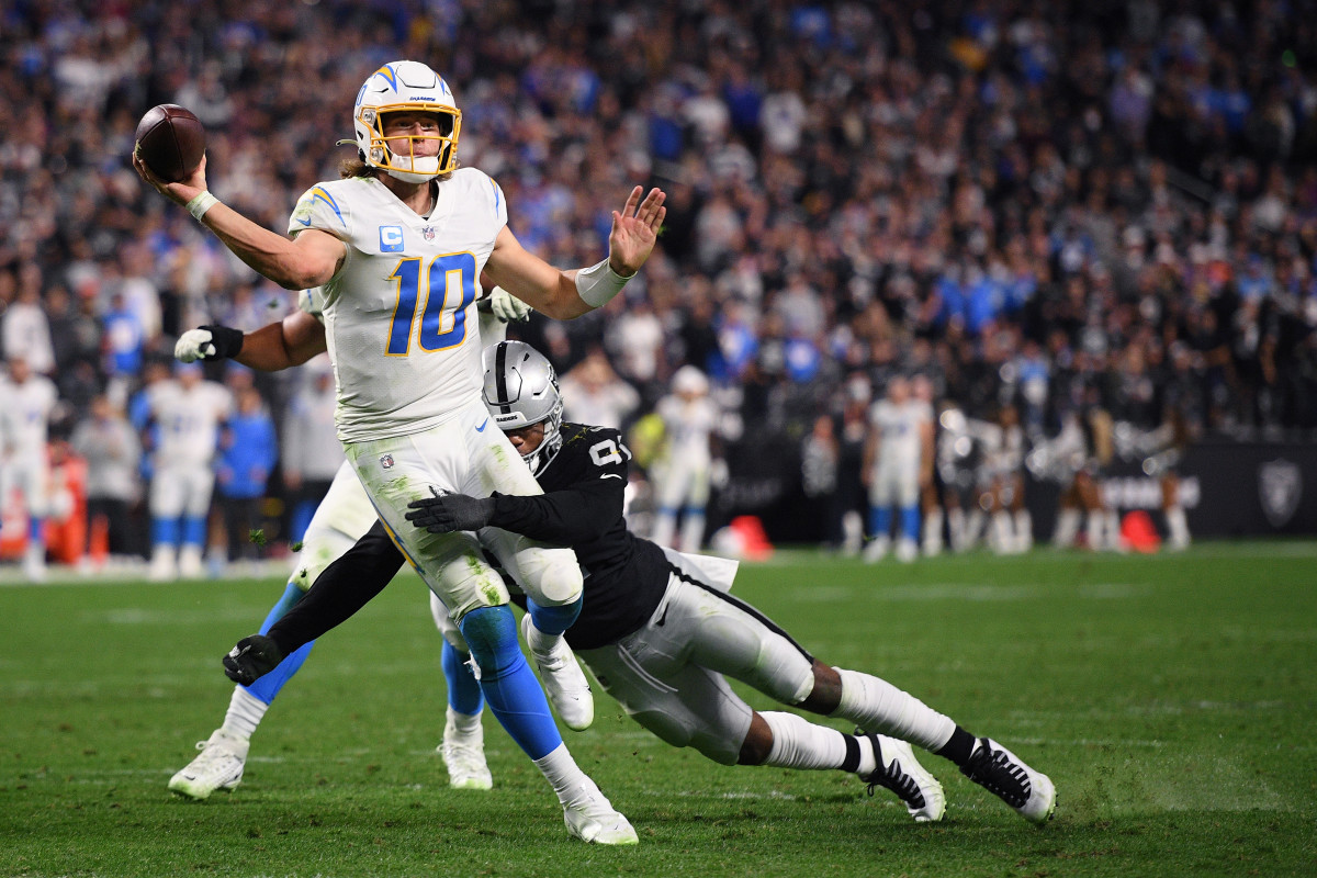 Jan 9, 2022; Paradise, Nevada, USA; Los Angeles Chargers quarterback Justin Herbert (10) throws a pass for a two-point conversion while tackled by Las Vegas Raiders defensive end Yannick Ngakoue (91) during the second half at Allegiant Stadium. Mandatory Credit: Orlando Ramirez-USA TODAY Sports