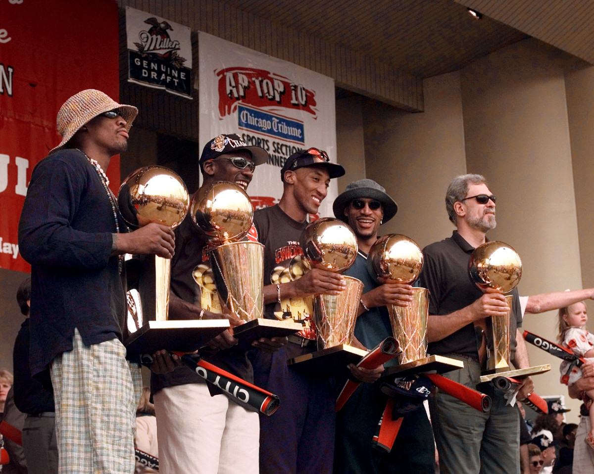 Chicago Bulls players, left to right, Ron Harper, Dennis Rodman, Scottie Pippen, Michael Jordan & coach Phil Jackson hold up the Bulls' five championship trophies at a rally in Grant Park.