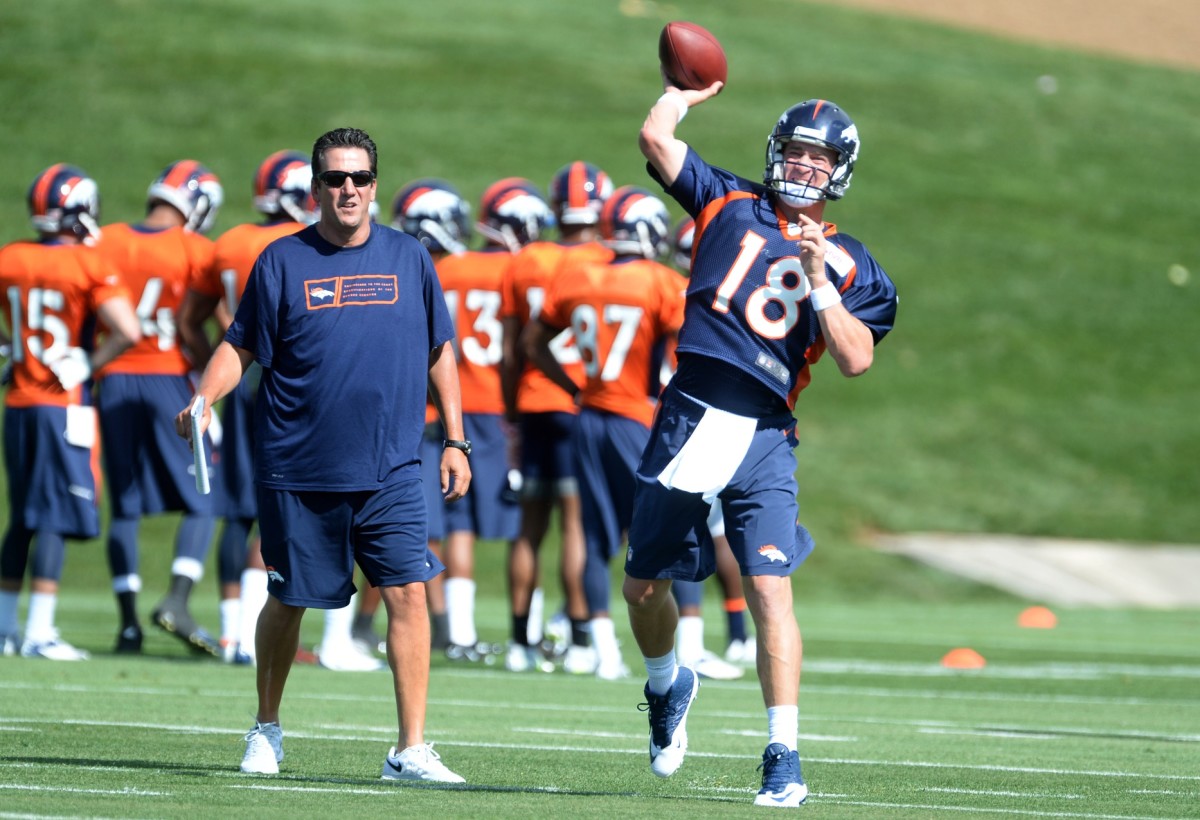 Denver Broncos quarterback Peyton Manning (18) passes next to quarterback coach Greg Knapp during training camp activities at the Broncos training facility.