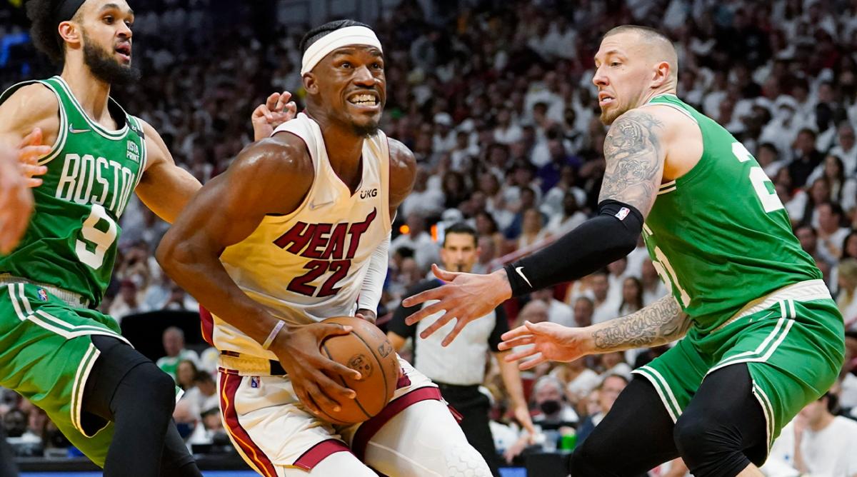 Miami Heat forward Jimmy Butler (22) drives to the basket between Boston Celtics guard Derrick White (9) and center Daniel Theis (27) during the second half of Game 1 of an NBA basketball Eastern Conference finals playoff series, Tuesday, May 17, 2022, in Miami.