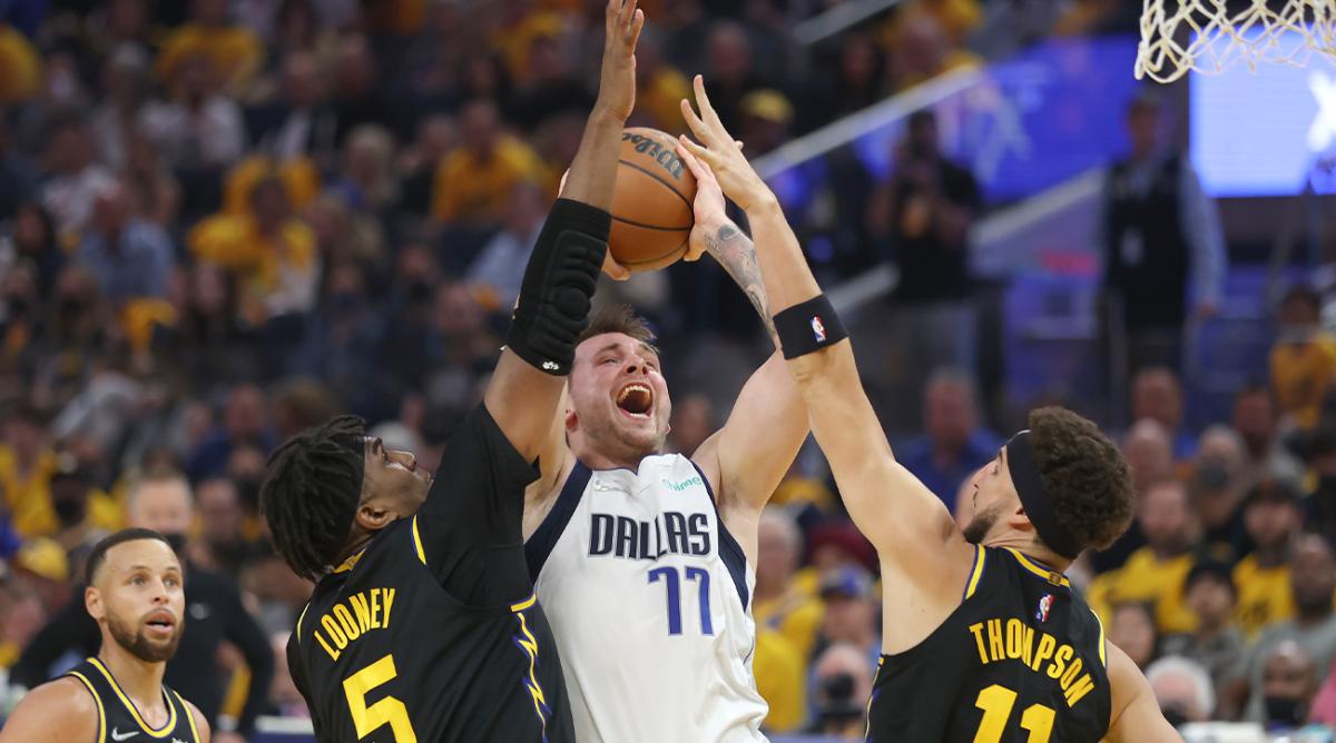 Dallas Mavericks guard Luka Doncic (77) shoots between Golden State Warriors center Kevon Looney (5) and guard Klay Thompson (11) during the first half of Game 1 of the NBA basketball playoffs Western Conference finals in San Francisco, Wednesday, May 18, 2022.