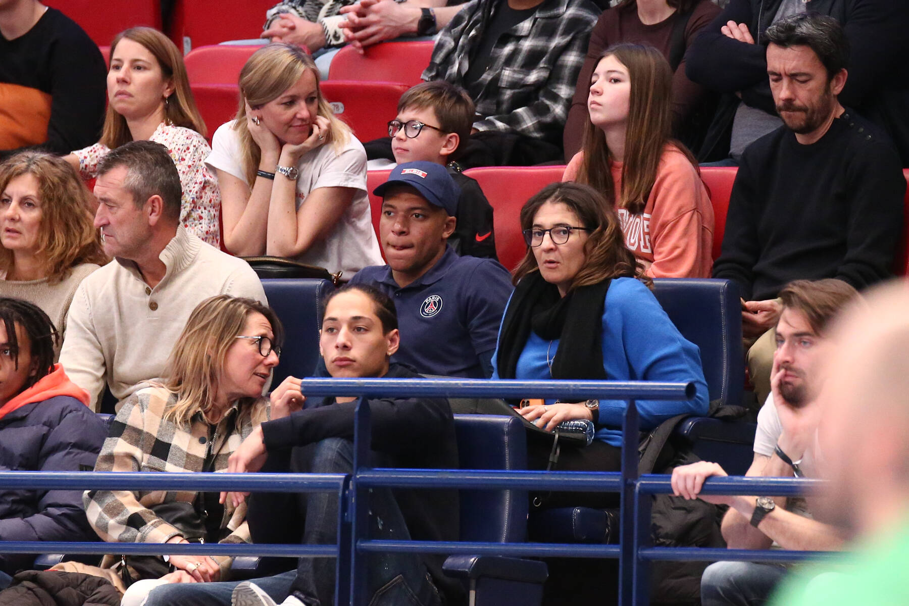 Kylian Mbappe pictured (center, wearing a baseball cap) watching a handball game between PSG and Nantes alongside his mother Fayza Lamari in March 2022
