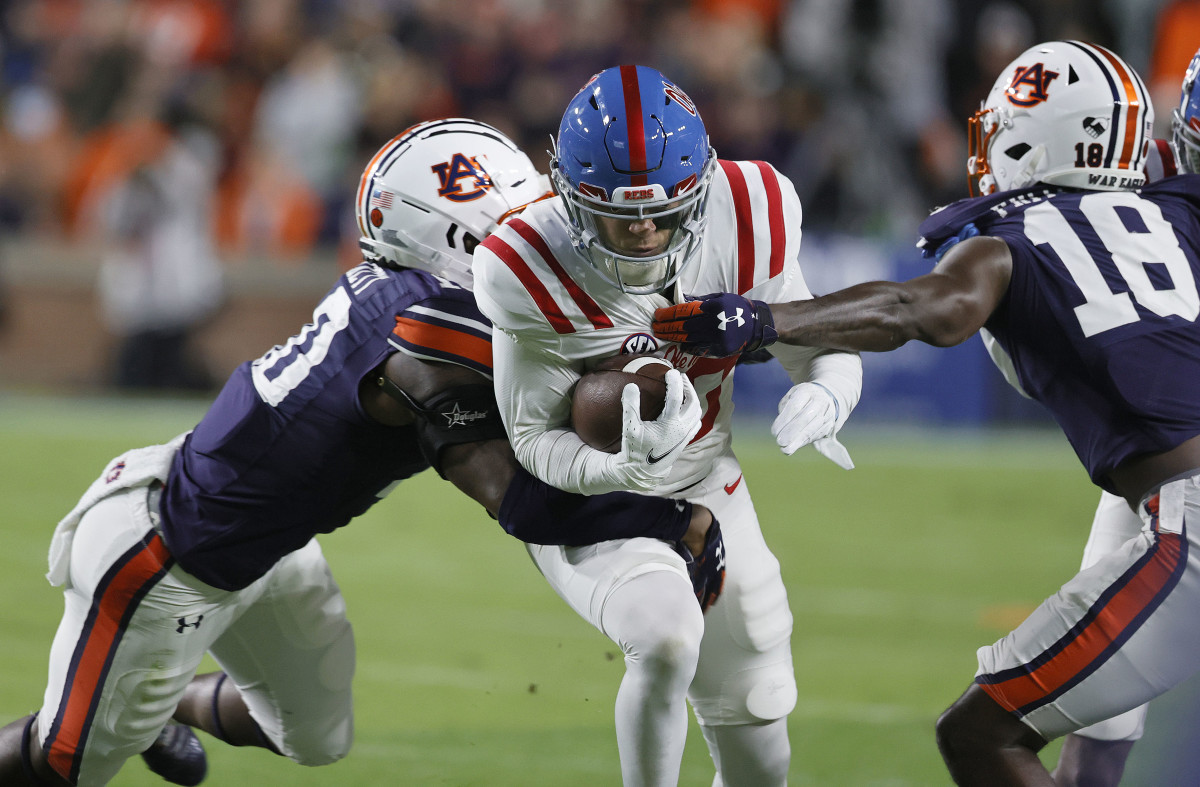 Oct 30, 2021; Auburn, Alabama, USA; Mississippi Rebels wide receiver John Rhys Plumlee (10) is tackled by Auburn Tigers cornerback Nehemiah Pritchett (18) and safety Zion Puckett (10) during the second quarter at Jordan-Hare Stadium. Mandatory Credit: John Reed-USA TODAY Sports