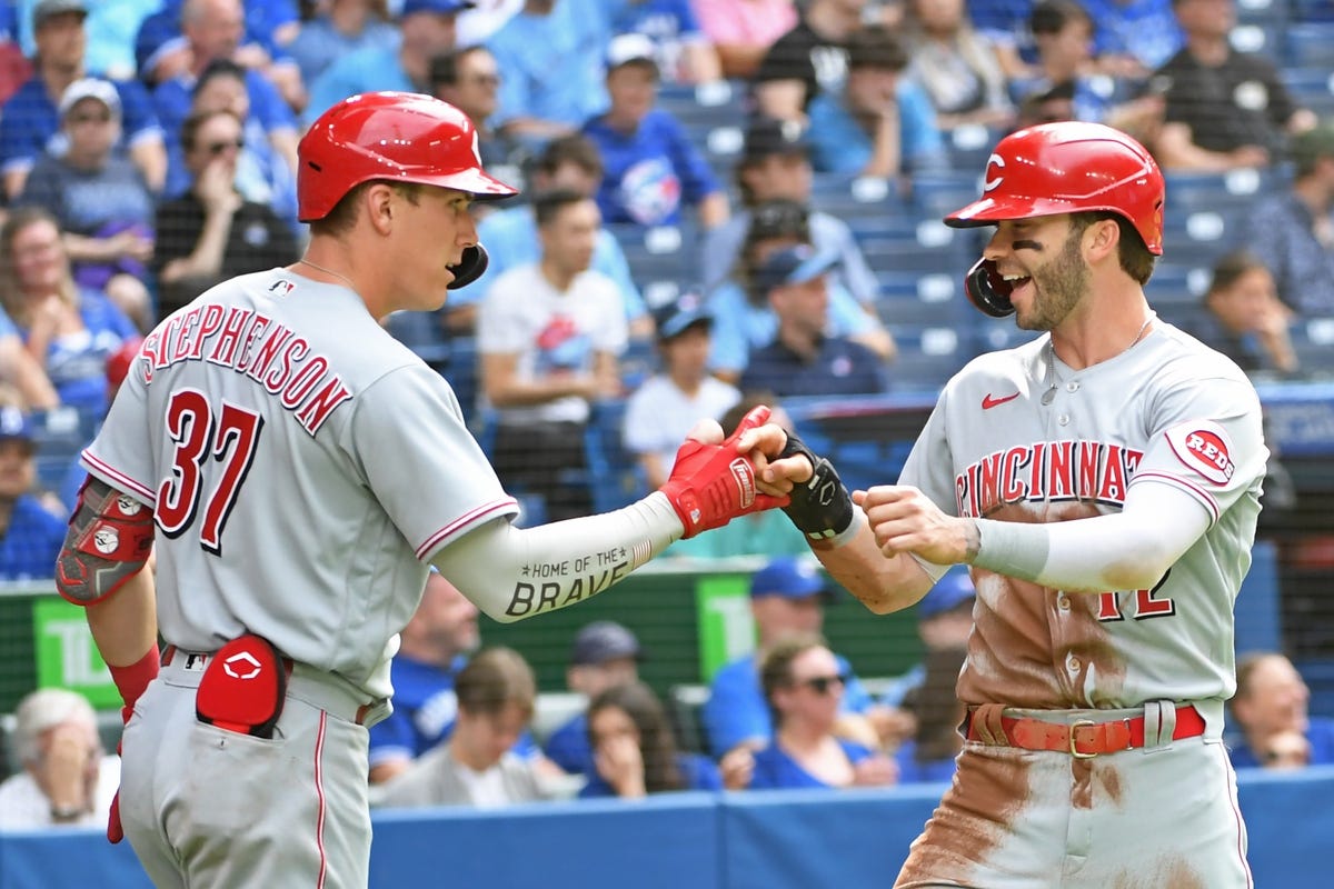 May 21, 2022; Toronto, Ontario, CAN; Cincinnati Reds right field Tyler Naquin (12) celebrates a run with catcher Tyler Stephenson (37) in the fourth inning against the Toronto Blue Jays at Rogers Centre. Mandatory Credit: Gerry Angus-USA TODAY Sports