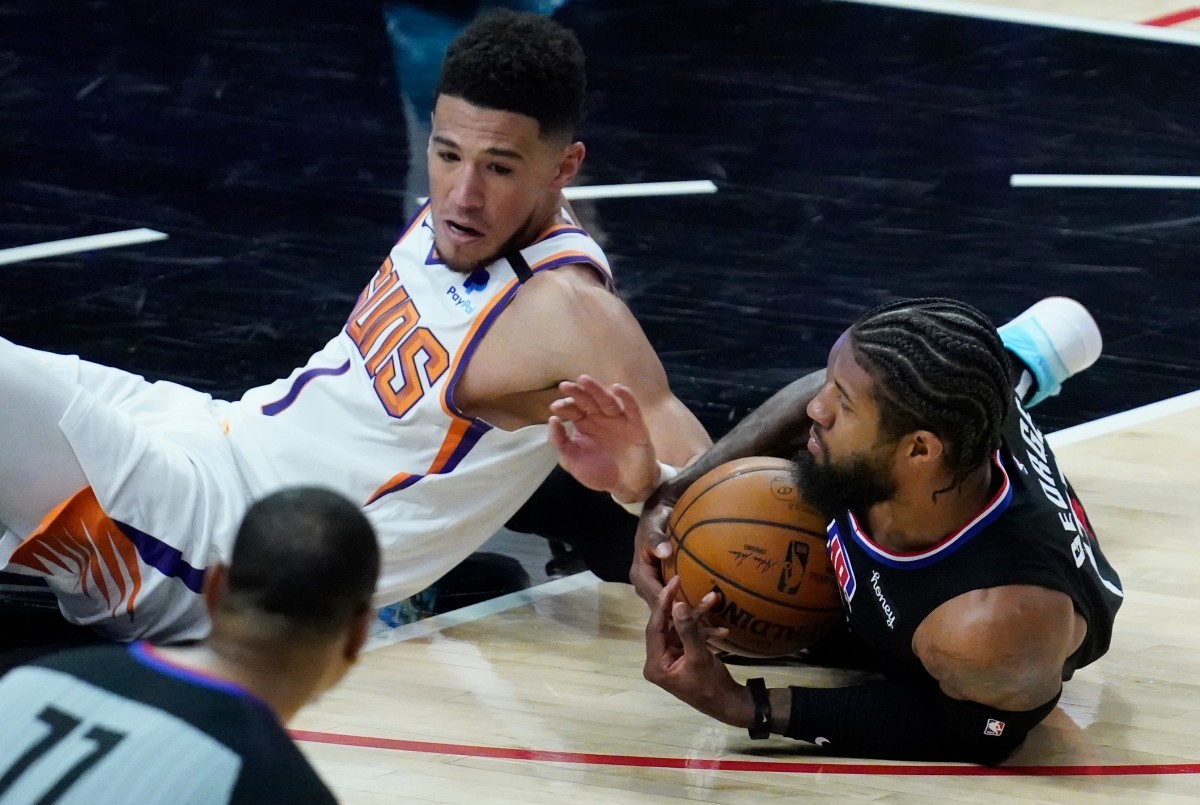 Apr 8, 2021; Los Angeles, California, USA; LA Clippers guard Paul George (13) goes to the floor to pick up a loose ball away from Phoenix Suns guard Devin Booker (1) during the third quarter at Staples Center. Mandatory Credit: Robert Hanashiro-USA TODAY Sports