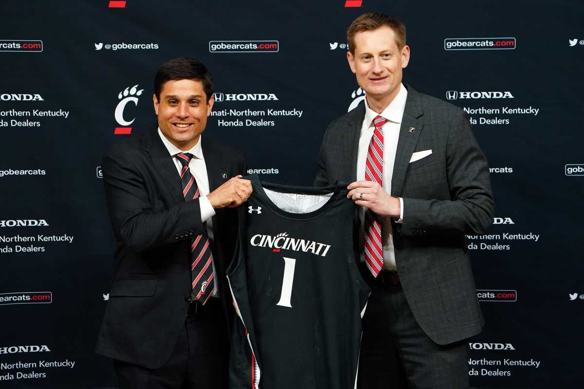 Wes Miller, left, is formally introduced as the new head men's basketball coach by University of Cincinnati Director of Athletics John Cunningham, Friday, April 16, 2021, at Fifth Third Arena in Cincinnati. Miller comes to UC from the University of North Carolina at Greensboro, where he was the longest-tenured coach in the Southern Conference and winningest coach in UNCG history.