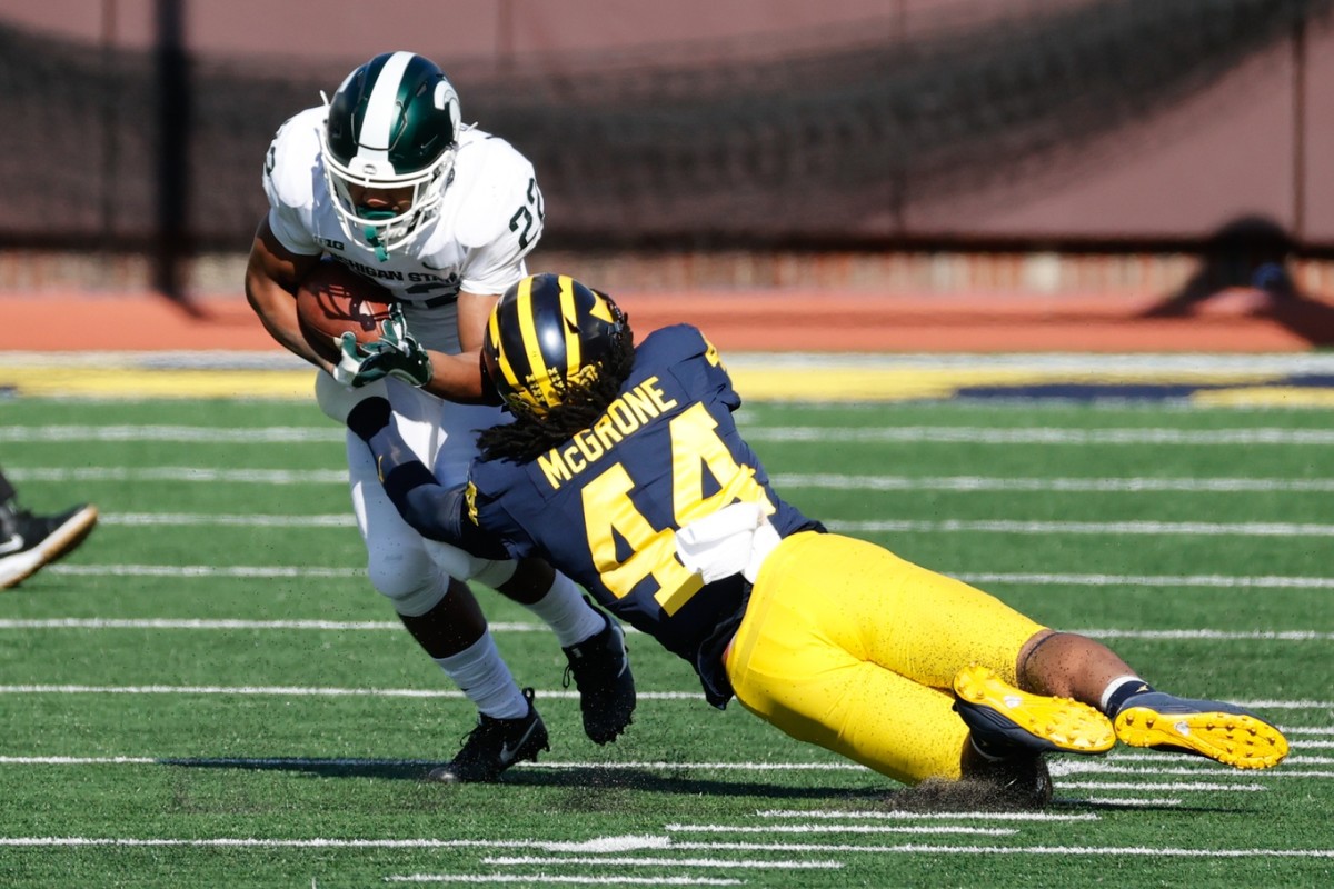 Michigan State Spartans running back Jordon Simmons (22) is tackled by DUPLICATE***Michigan Wolverines defensive back Joshua Luther (44)***Michigan Wolverines linebacker Cameron McGrone (44) in the first half at Michigan Stadium.