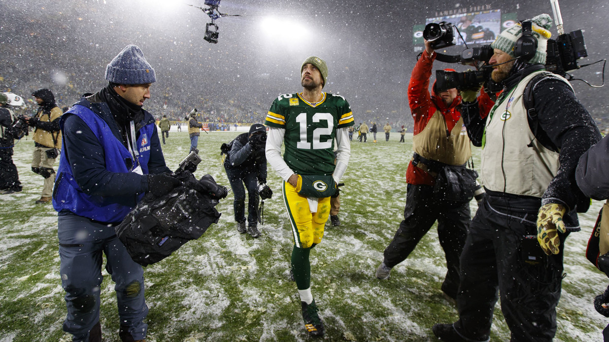 Aaron Rodgers walks off Lambeau Field in the snow with cameras pointed at him