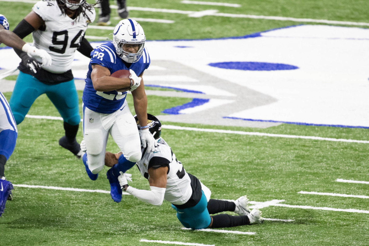 Jan 3, 2021; Indianapolis, Indiana, USA;Indianapolis Colts running back Jonathan Taylor (28) runs the ball while Jacksonville Jaguars cornerback Kobe Williams (31) defends in the second half at Lucas Oil Stadium.