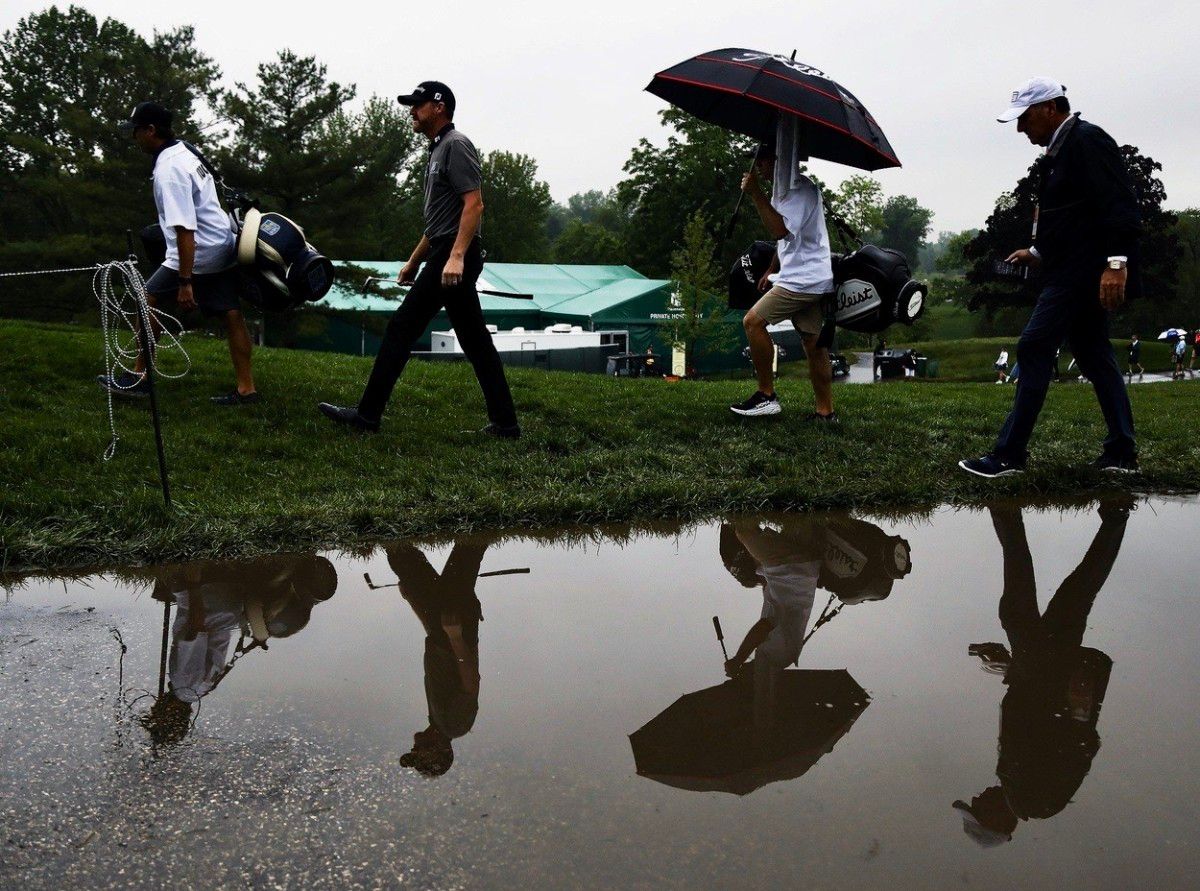 Golfers navigate a wet and dark environment at Muirfield Village on Thursday.