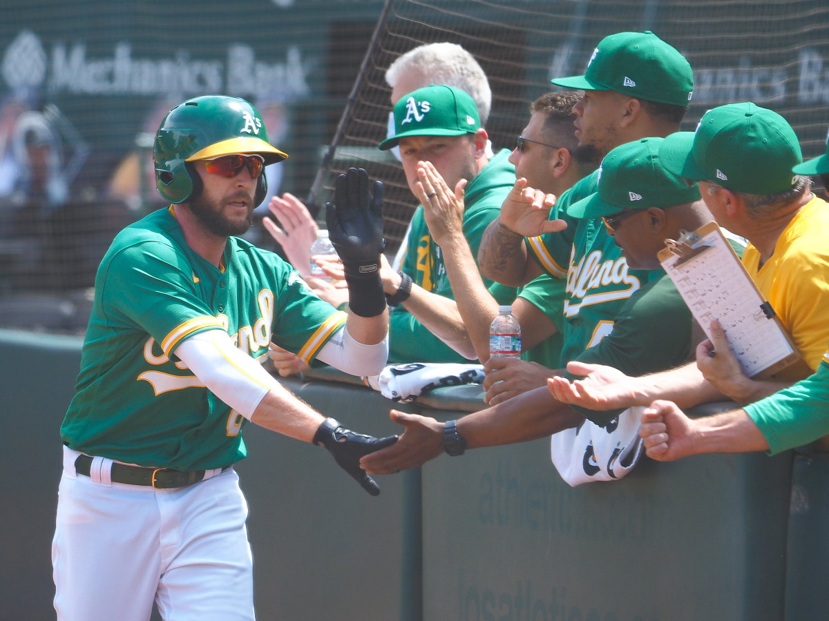 Oakland Athletics second baseman Jed Lowrie (8) high fives teammates after scoring a run against the Los Angeles Angels during the sixth inning at RingCentral Coliseum.