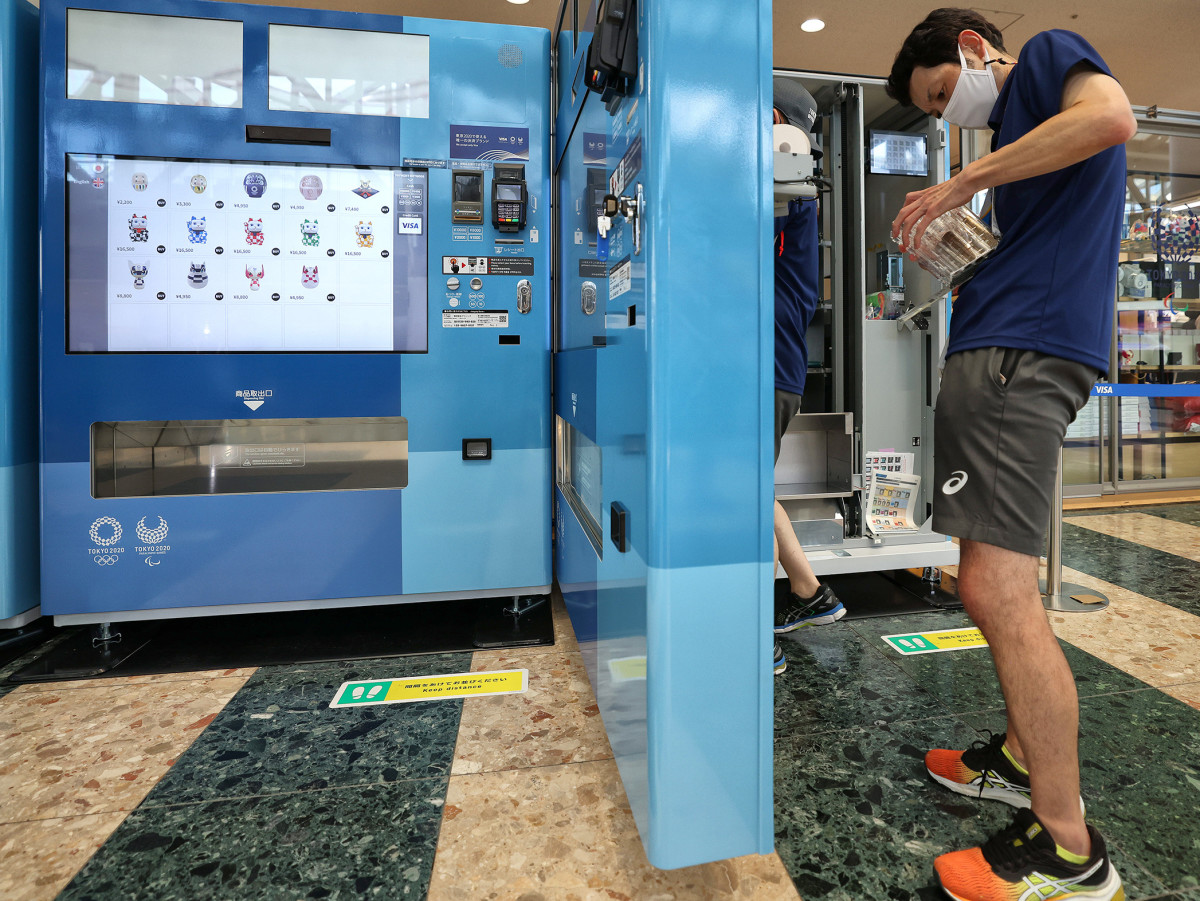 A customer buys an item from a vending machine at the Tokyo Olympics.